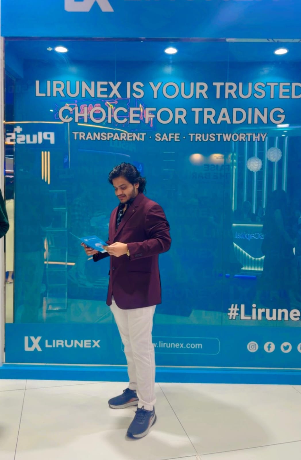 Meet Rafaliya in a maroon blazer reading a brochure at a Lirunex trading event